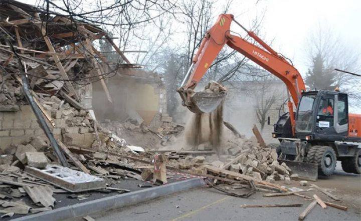 Excavator demolishing a building in Mashtagha as the railway corridor is cleared