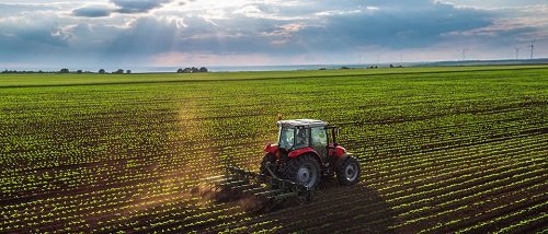 Agricultural machinery working in a field in a television report about rising farm costs in Azerbaijan.