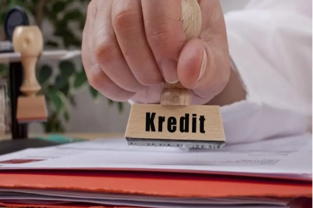 A person stamping the word Kredit on loan paperwork