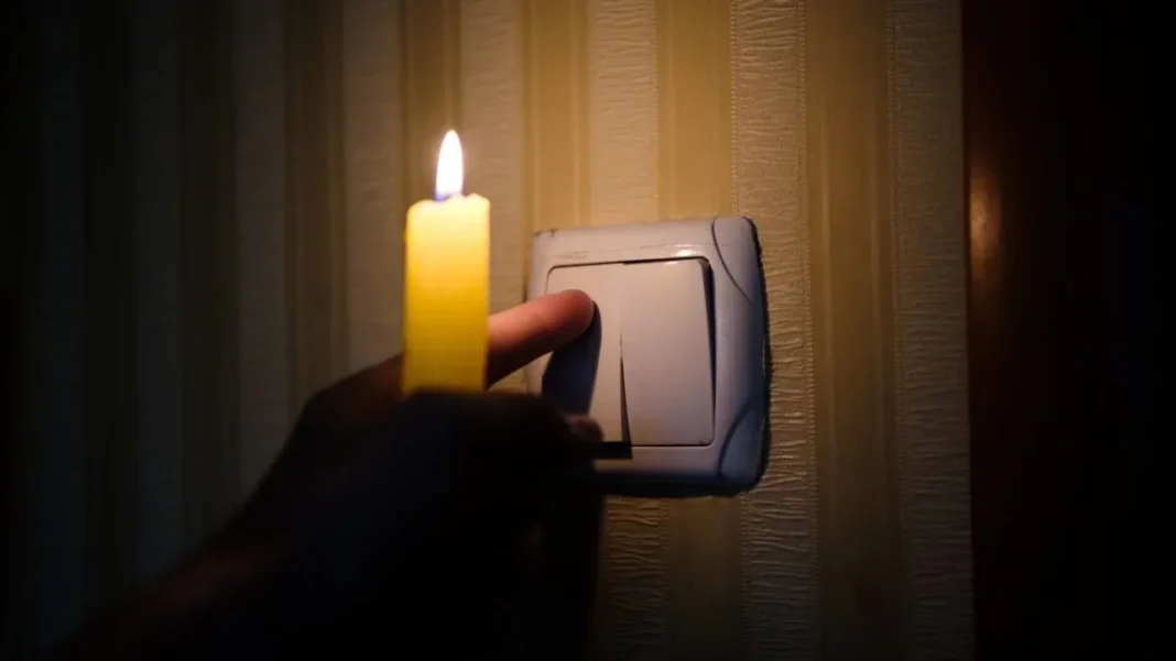 Candle beside a light switch during a power outage
