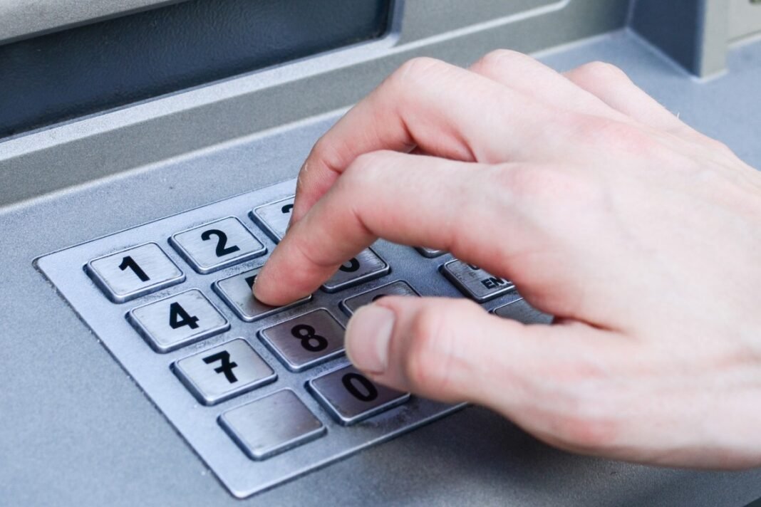 Person entering a PIN at an ATM, illustrating pension payments