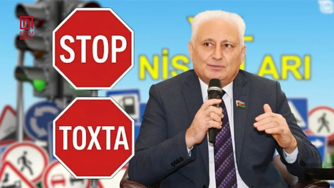 Azerbaijani lawmaker Hikmet Babaoglu beside Stop and Toxta road sign graphics