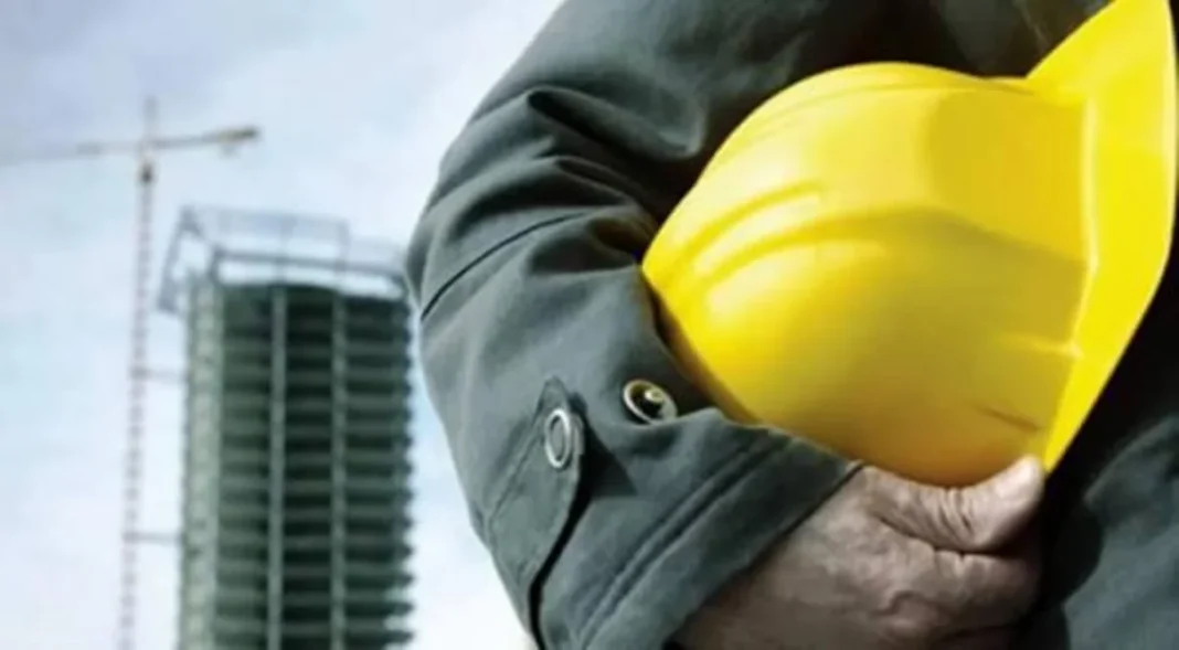Construction worker in a hard hat near a crane and building site