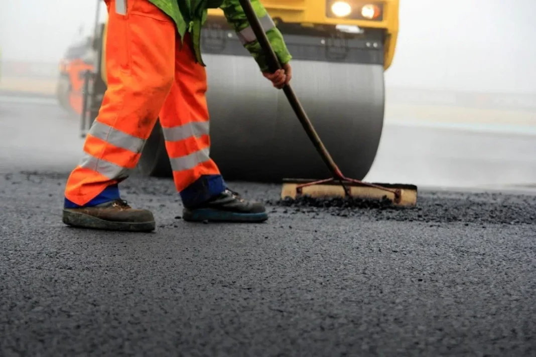 Road worker and asphalt roller during resurfacing work