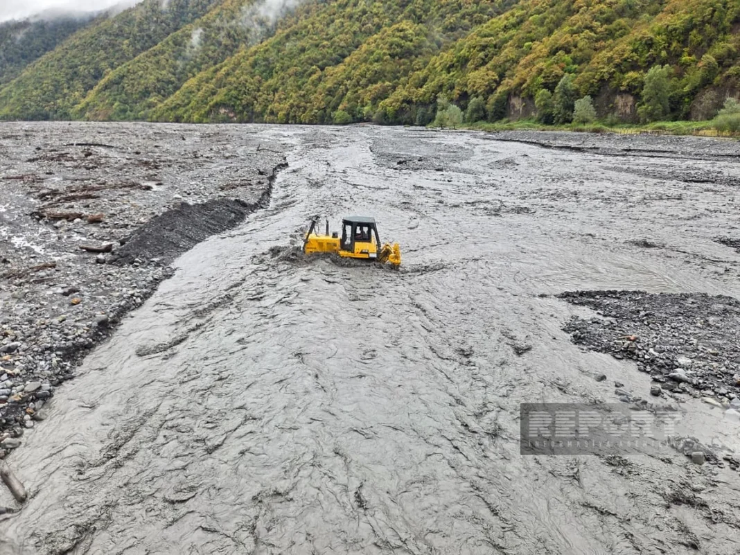 Heavy equipment reinforcing riverbanks after flooding in Zagatala